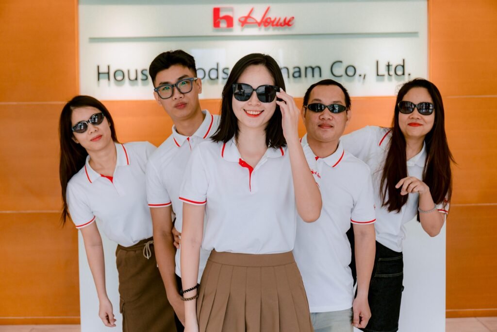 Group of five colleagues wearing polo shirts and sunglasses indoors at company office.
